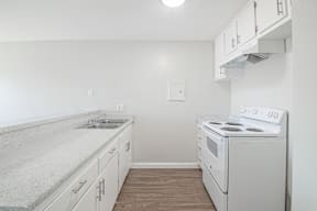 A kitchen with a stove, sink, and cabinets.