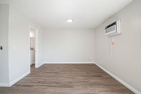 A room with a wood floor and a wall-mounted air conditioner.