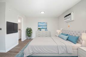 A bedroom with a bed, nightstand, and a painting on the wall.
