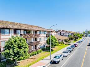 A row of houses with cars parked on the street.