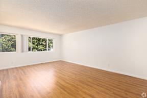 Empty room with wooden flooring and white walls.