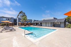 A swimming pool surrounded by a concrete patio and a metal fence.