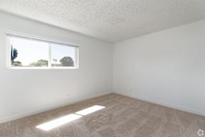 A room with a carpeted floor and a window letting in sunlight.