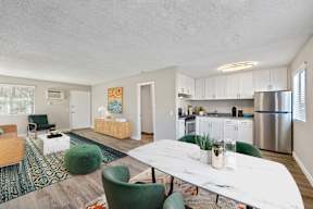 A modern kitchen with a white table and green chairs.
