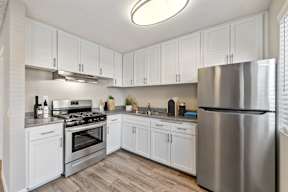 A modern kitchen with white cabinets and stainless steel appliances.