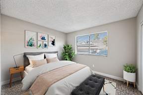 A bedroom with a large bed and a plant on the windowsill.
