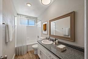 A bathroom with a sink, mirror, and shower.