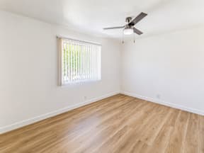A room with a ceiling fan and a window with blinds.