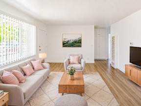 A living room with a grey couch, a coffee table, and a painting on the wall.