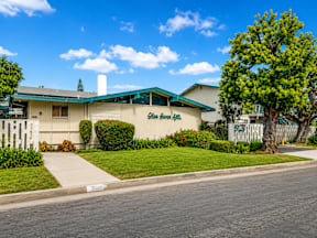 A building with a green awning and a sign that says "Garden Inn" is surrounded by a well-manicured lawn and a sidewalk.