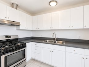 A kitchen with white cabinets and a stainless steel stove.