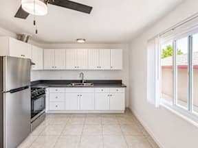 A kitchen with white cabinets and a stainless steel refrigerator.