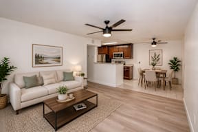 A living room with a white couch, a coffee table, and a dining table with chairs.