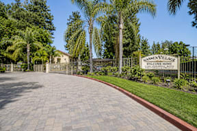 A sign that says "Hansen Village Welcome Home" is in front of a gated entrance.