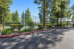 A parking lot with a red curb and a fence.