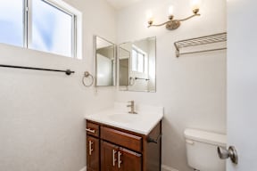 A white bathroom with a sink, toilet, and a window.