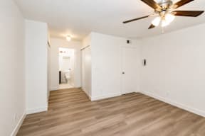 A room with a ceiling fan and wooden flooring.
