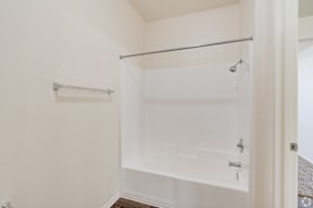 A white shower stall with a glass door and a metal rod above it.