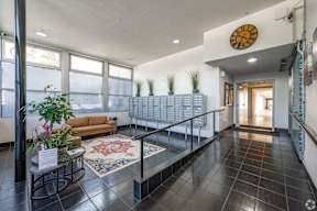 A hallway with a clock on the wall and a railing on the floor.