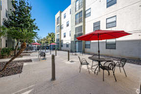 A red umbrella is on a table outside a building.
