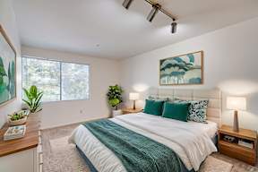 A bedroom with a large bed and a painting on the wall.