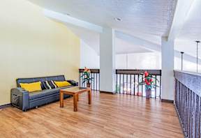 A living room with a black couch and a wooden coffee table.