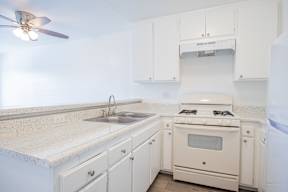 A white kitchen with a fan on the ceiling.