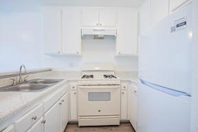 A white kitchen with a fridge on the right.