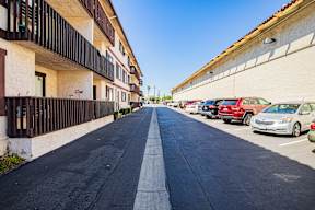 A long, narrow road with cars parked on the side.