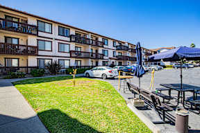 A car is parked in front of a building with a balcony.