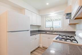 A kitchen with a white refrigerator, a white stove, and white cabinets.