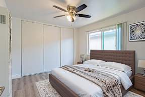 A bedroom with a large bed and a ceiling fan.