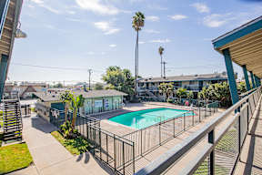 A pool surrounded by a fence and a building in the background.