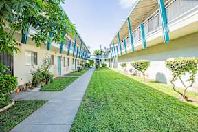 A long, narrow walkway between two buildings with greenery on the sides.