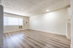 A room with wooden flooring and a window with blinds.
