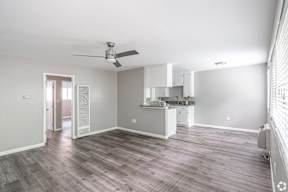 A spacious room with a ceiling fan and a kitchenette.