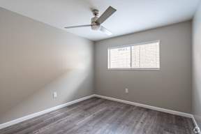A room with a ceiling fan and a window with blinds.
