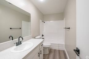 A white bathroom with a sink, toilet, and shower.
