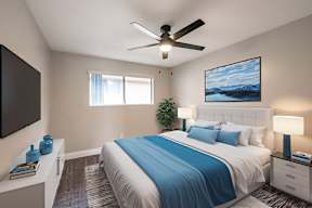 A bedroom with a bed, a ceiling fan, and a painting on the wall.