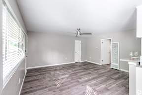 A room with a ceiling fan and a window with blinds.