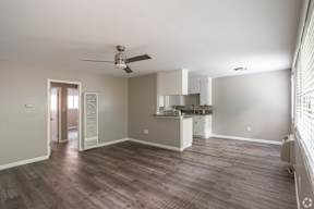 A spacious room with a kitchenette and a ceiling fan.
