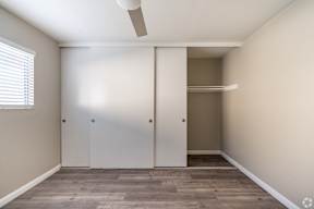 A room with a white ceiling fan and two white closet doors.