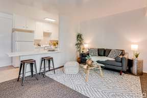 a living room with a couch and a kitchen with a bar and stools at University Park, Azusa, 91702