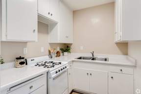 a kitchen with white cabinets and a stove and sink at University Park, Azusa, CA