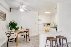 a living room with a kitchen with a bar and stools and a ceiling fan at University Park, California, 91702