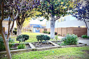 a garden with trees and shrubs in front of a house at Fiesta Apts, Lompoc, CA 93436