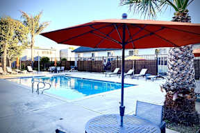 a pool with a table and umbrella next to it at Fiesta Apts, Lompoc, CA
