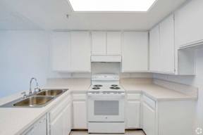 a kitchen with white cabinets and white appliances and a sink at Flamingo Garden Senior Apts, El Monte, CA 91732