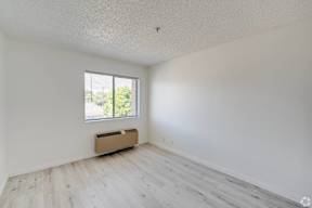 an empty room with white walls and a window at Huntington Terrace North Senior, California