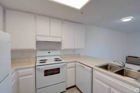 a kitchen with white appliances and white cabinets at Flamingo Garden Senior Apts, El Monte